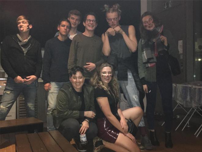 A group of friends pose together - some of them have whiskers drawn on their face because it's Halloween.